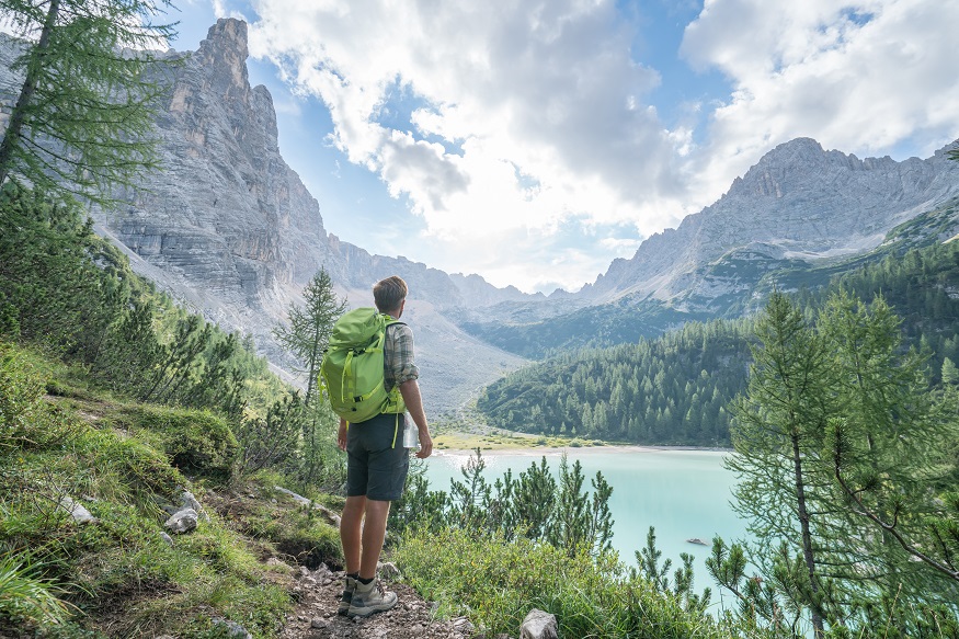 Hiking Man Contemplating Alpine Lake In Italy