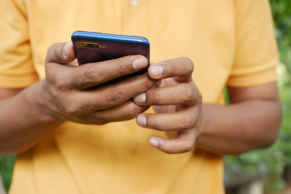 Active mobile user browsing fast cellular data on a modern 5G smartphone outdoors