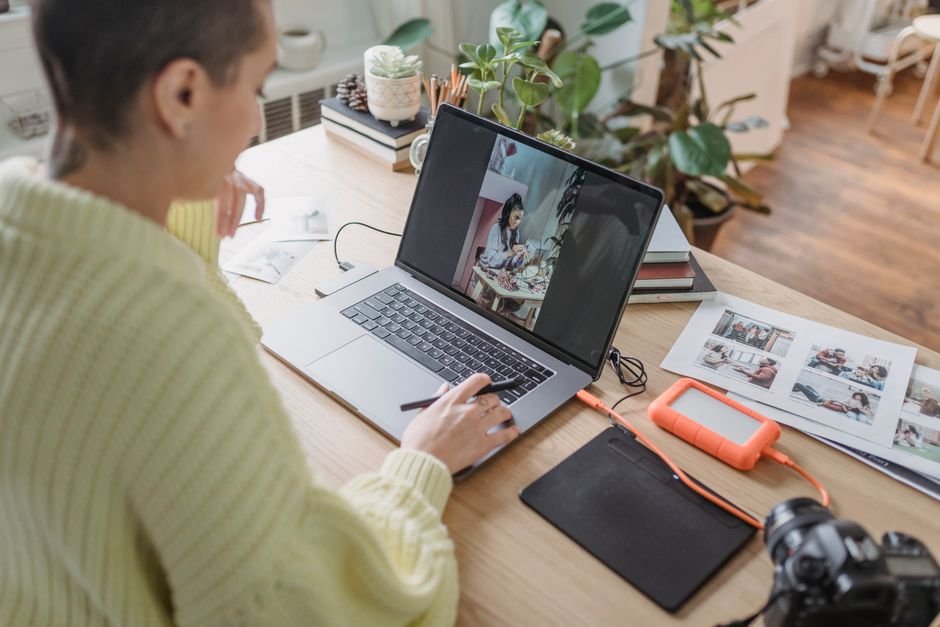 Creative editor retouching photographic portraits on laptop and graphics tablet