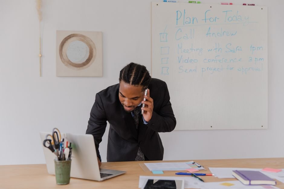Small business owner working on laptop in modern office setting with financial charts