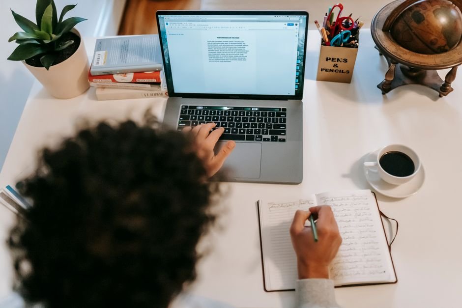 Creative blogger typing focused content on screen with warm beverage on wooden desk