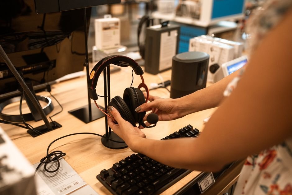 Shopper testing audio headset ergonomics and sound quality in electronics showroom