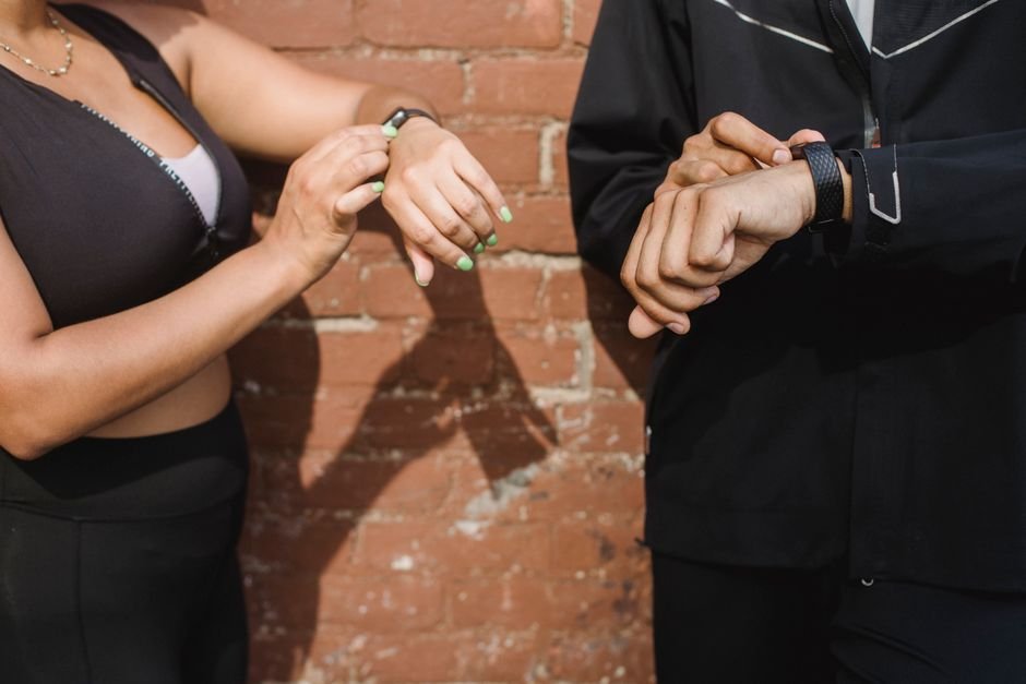 Athletes checking heart rate and activity metrics on wrist fitness trackers outdoors