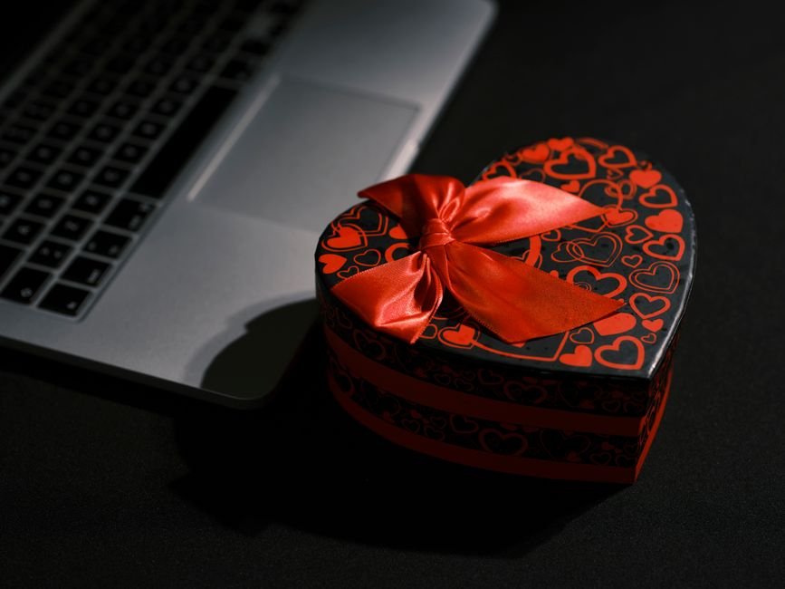 Elegant gift box next to laptop representing practical gadget presents for friends and family