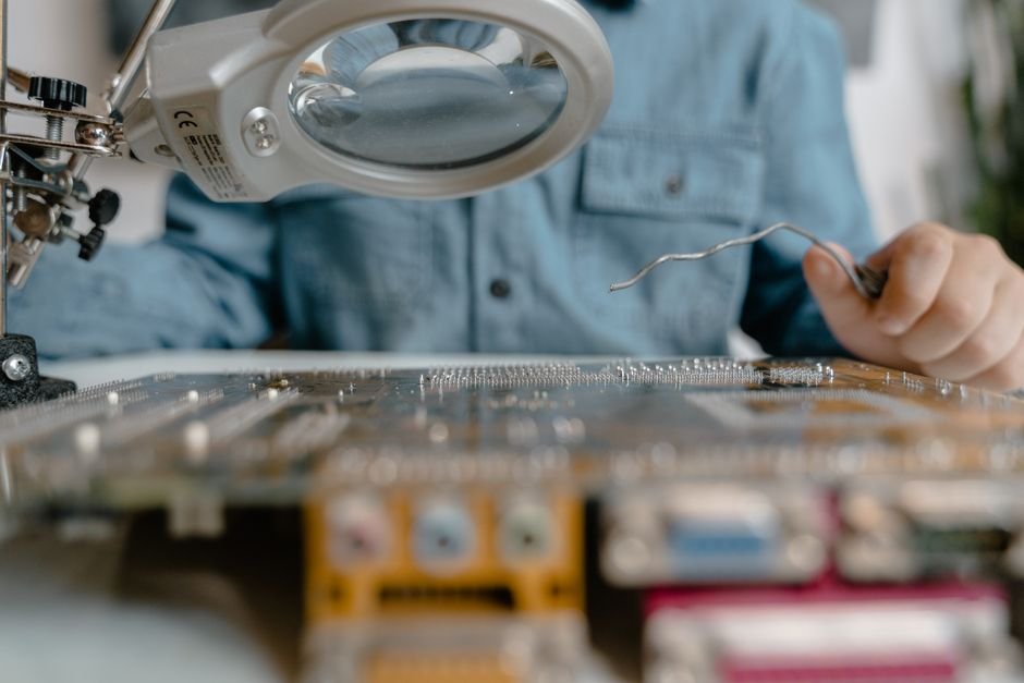 Technician inspecting electronic circuitry and serial numbers with magnifying glass