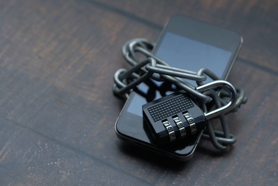 Smartphone symbolically secured with heavy chain and padlock against data theft