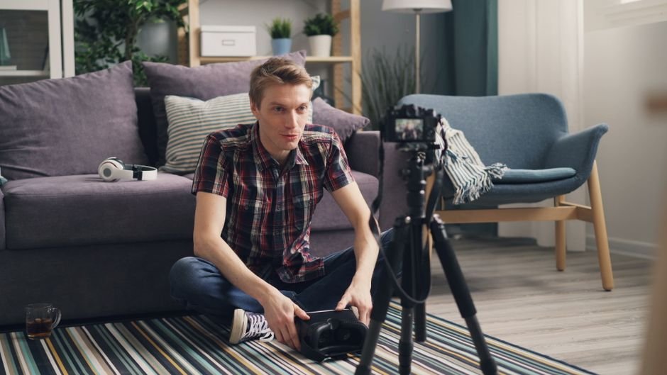 Young creator filming creative video content from home living room with portable equipment