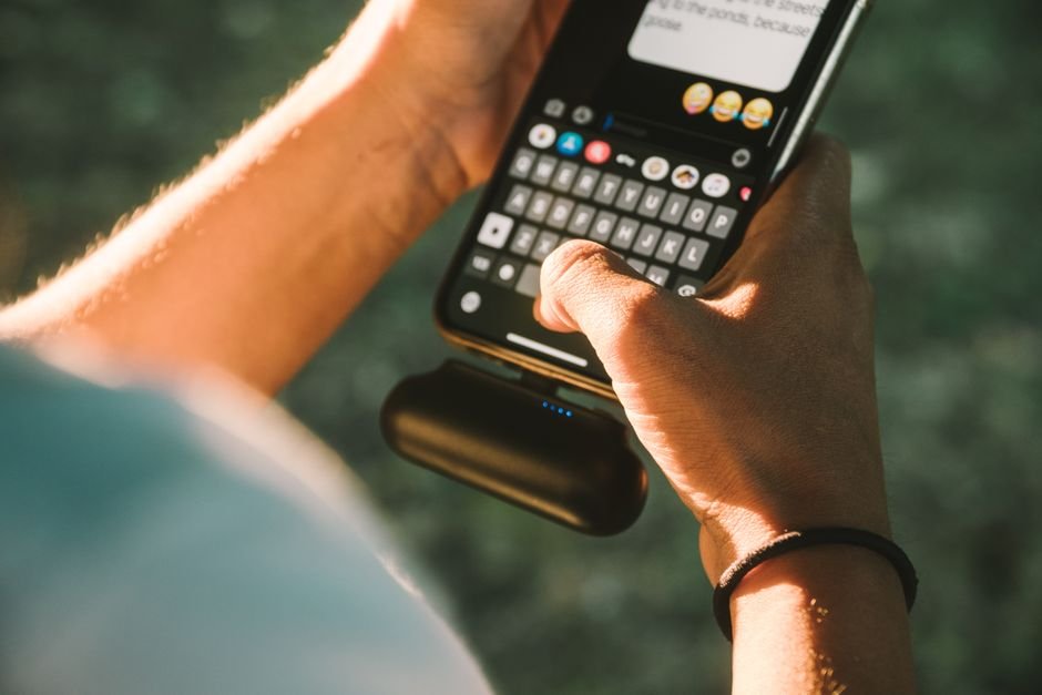 Traveler comfortably using smartphone connected to portable battery pack on outdoor trip