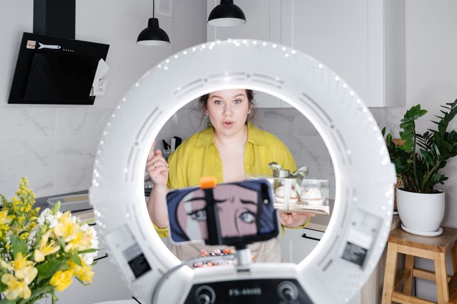 Vlogger filming video tutorial with smartphone mounted on ring light tripod stand