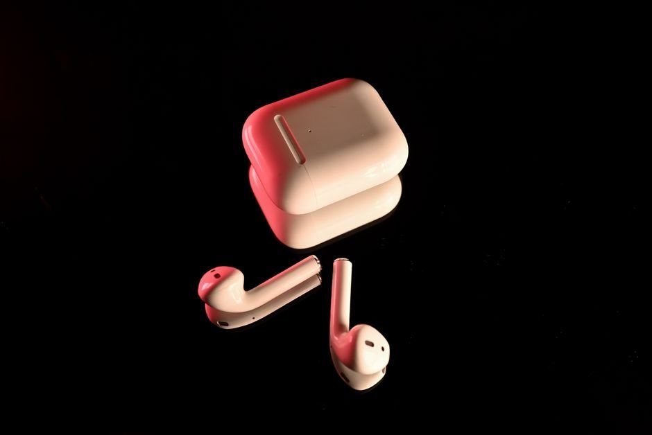 Modern TWS earbuds resting in illuminated charging case showing battery status